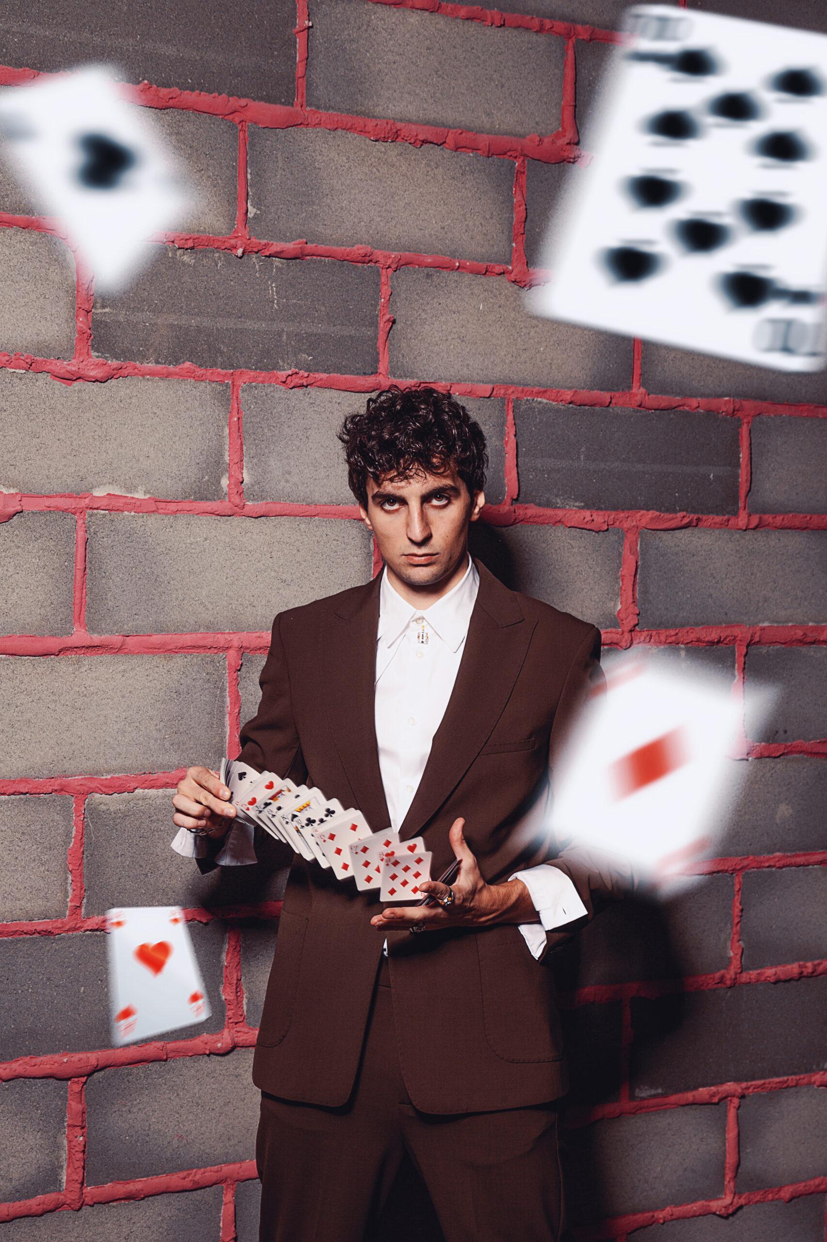 uomo che guarda l'obbiettivo con le carte che volano intorno a lui