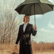 ragazzo biondo indossando un completo nero sotto l'ombrello