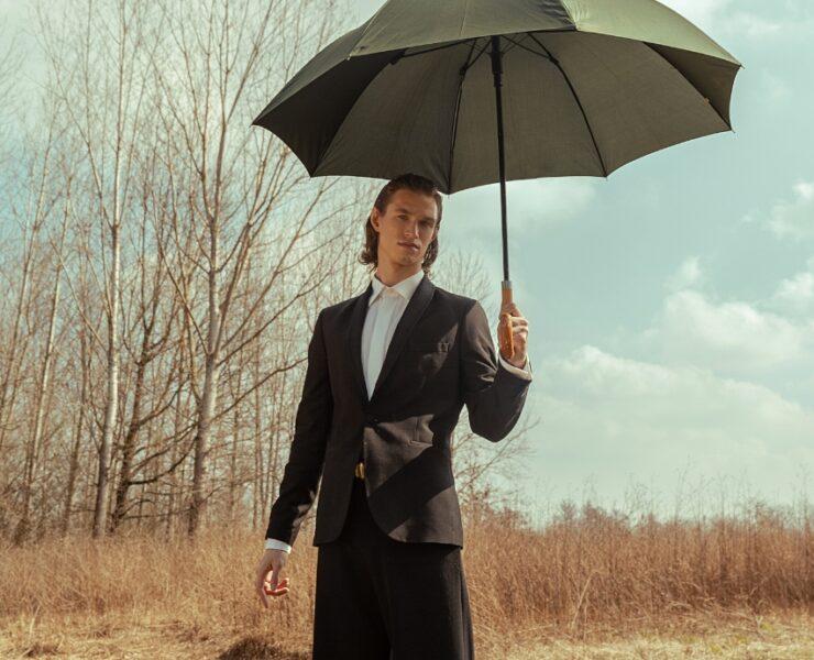 ragazzo biondo indossando un completo nero sotto l'ombrello