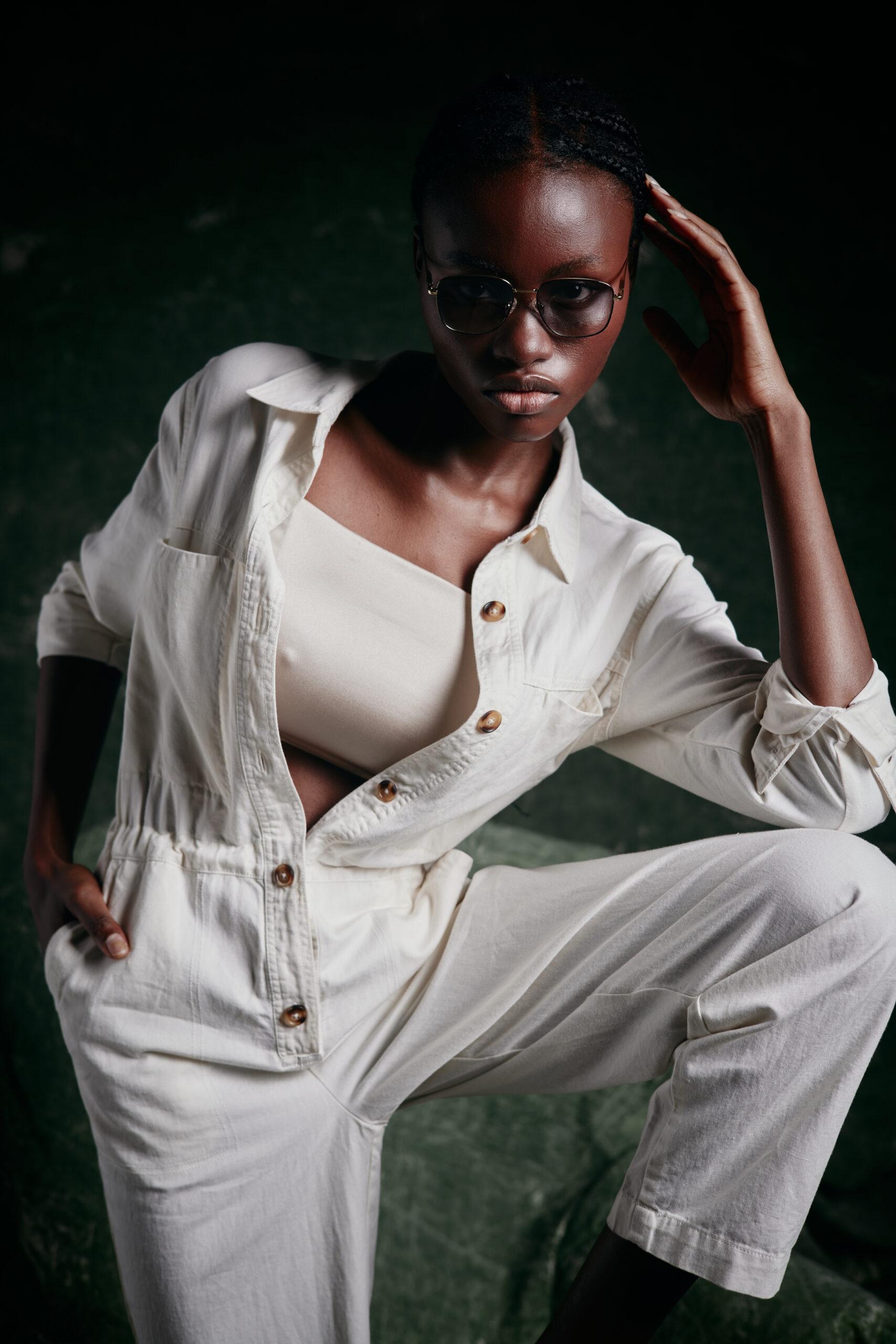 modella africana in una tuta color crema e occhialli da sole