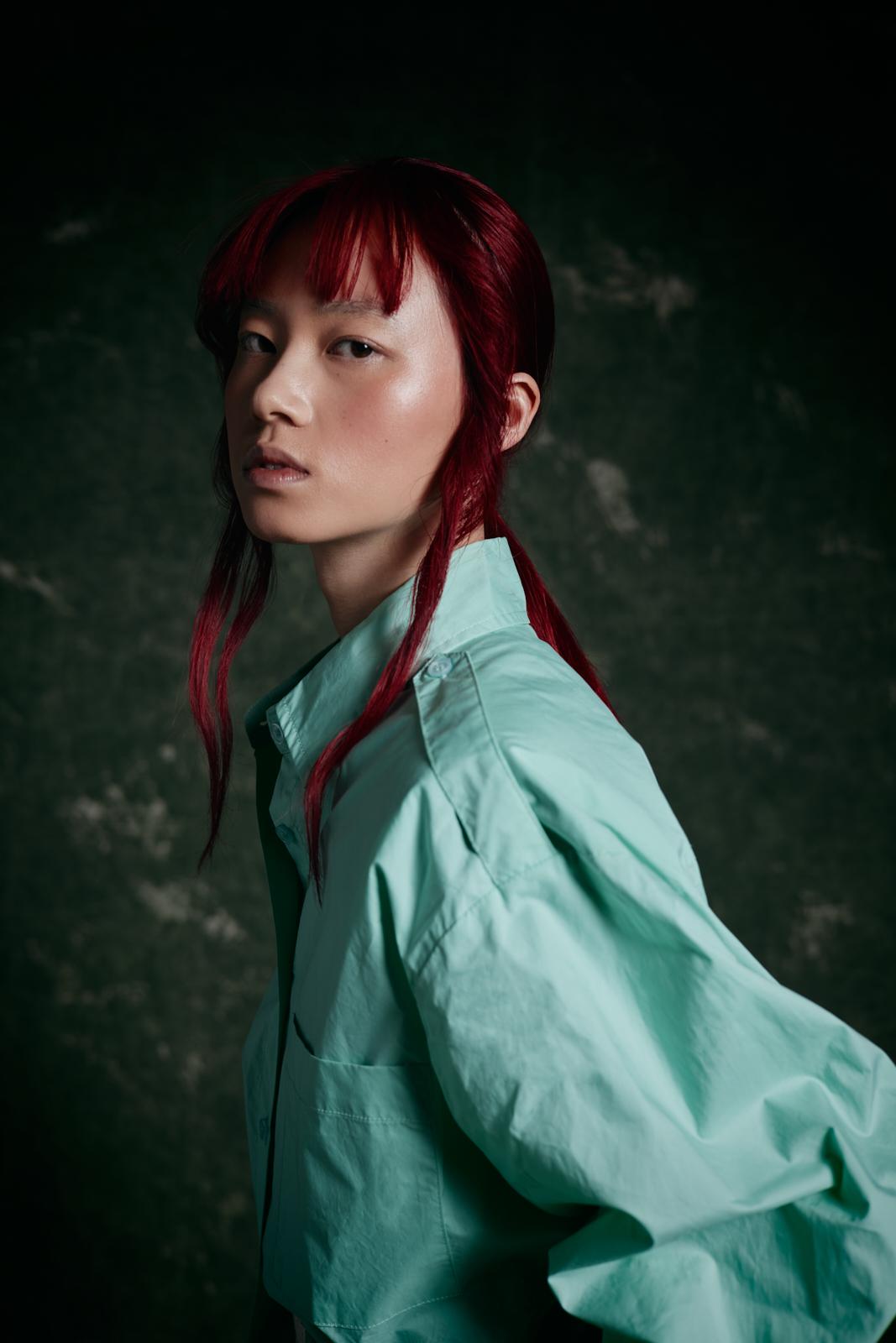 modella asiatica con capelli rossi di profilo
