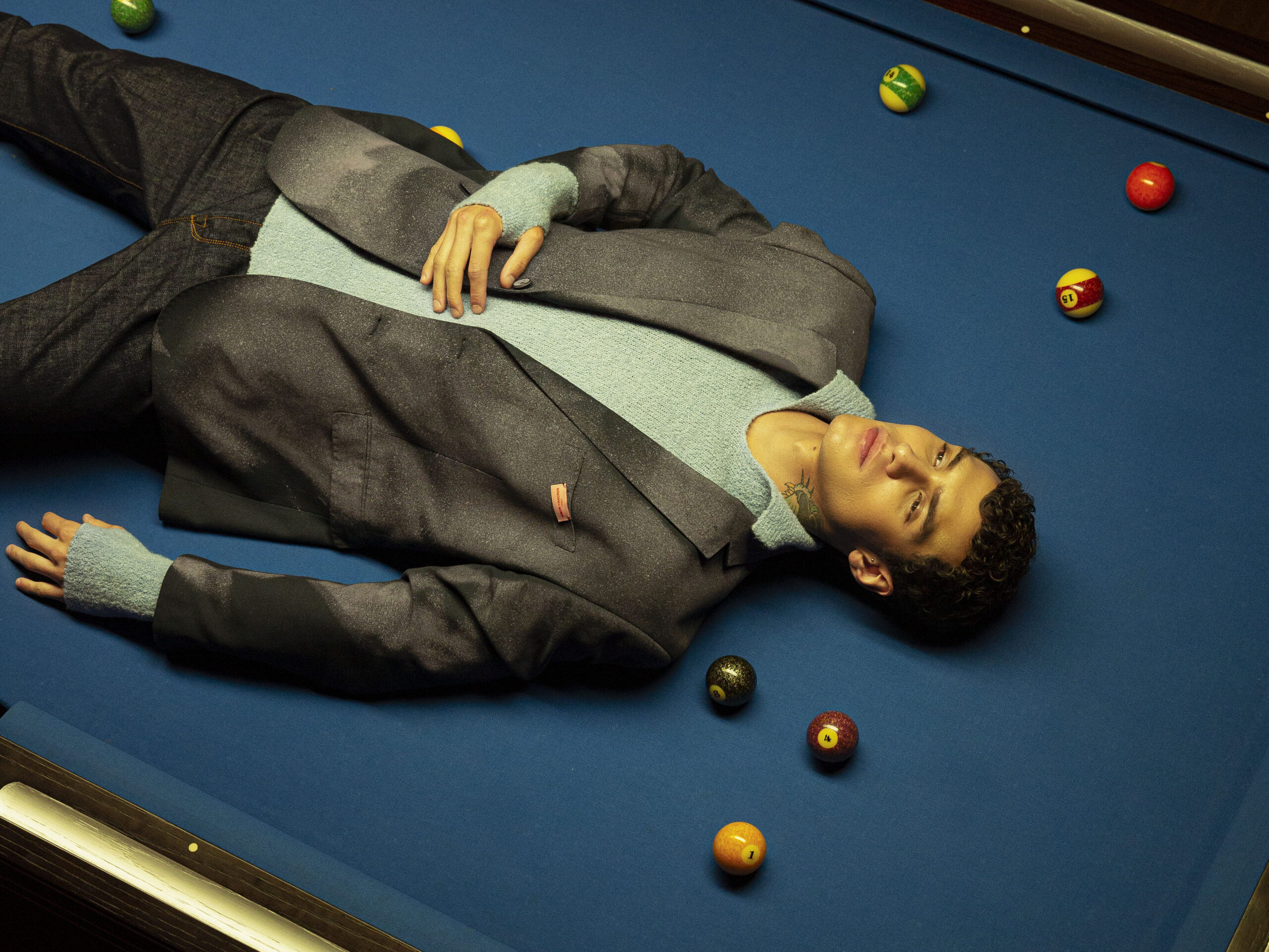 MAN LYING ON A BLUE BILLIARD TABLE